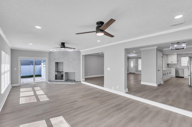 unfurnished living room with crown molding, a fireplace, light hardwood / wood-style floors, and a textured ceiling