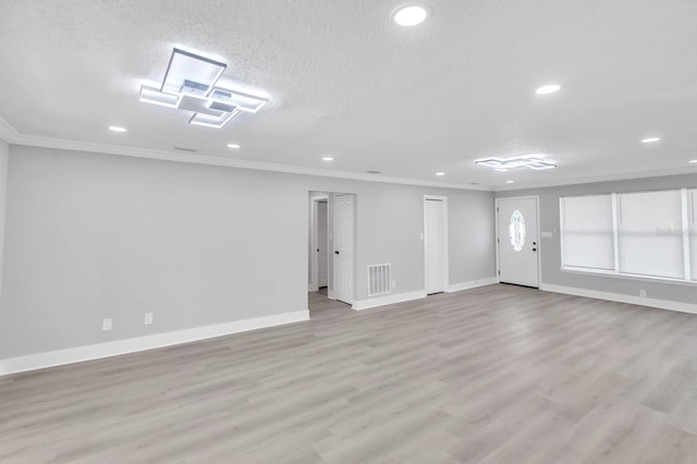 spare room with ornamental molding, light wood-type flooring, and a textured ceiling