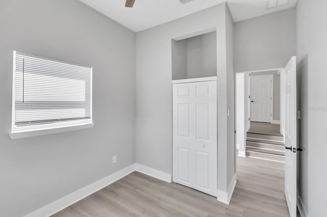 unfurnished bedroom featuring ceiling fan, light wood-type flooring, and a closet