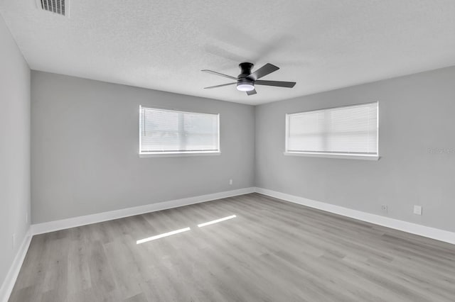 unfurnished room with ceiling fan, light hardwood / wood-style flooring, and a textured ceiling