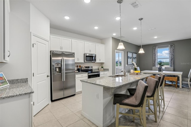 kitchen with sink, light stone counters, stainless steel appliances, a kitchen island with sink, and white cabinets