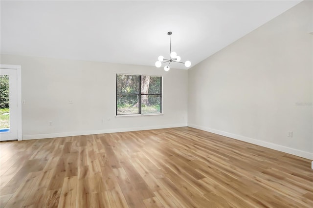 unfurnished room featuring an inviting chandelier, vaulted ceiling, and light hardwood / wood-style flooring