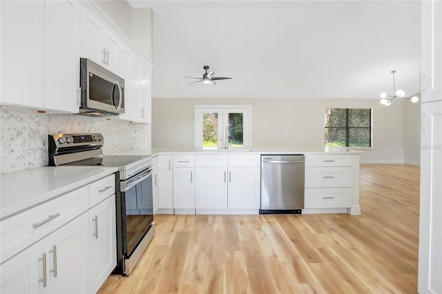 kitchen featuring white cabinetry, a healthy amount of sunlight, stainless steel appliances, and hanging light fixtures