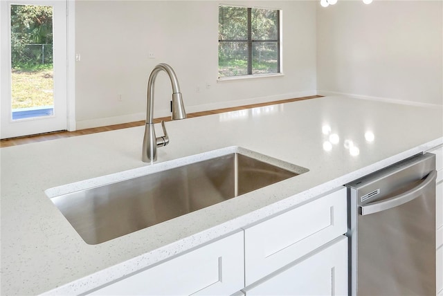 kitchen with dishwasher, light stone countertops, sink, and a wealth of natural light