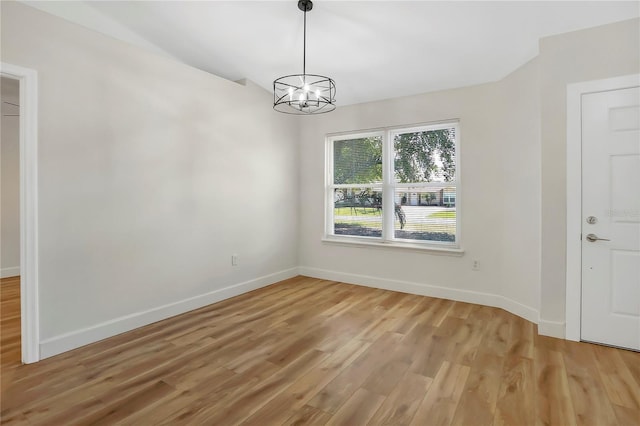 spare room featuring wood-type flooring and a chandelier