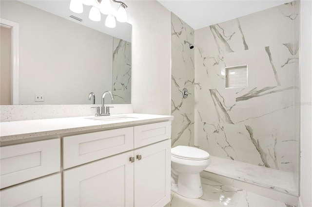 bathroom with vanity, toilet, and a tile shower