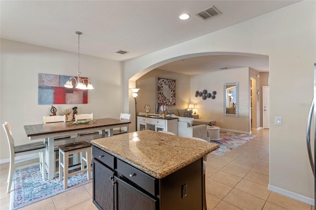 kitchen with light tile patterned flooring, dark brown cabinetry, decorative light fixtures, a chandelier, and a kitchen island