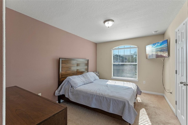 bedroom featuring light carpet and a textured ceiling