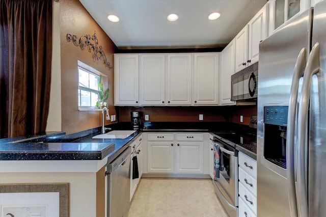 kitchen with sink, white cabinetry, dark stone countertops, appliances with stainless steel finishes, and kitchen peninsula