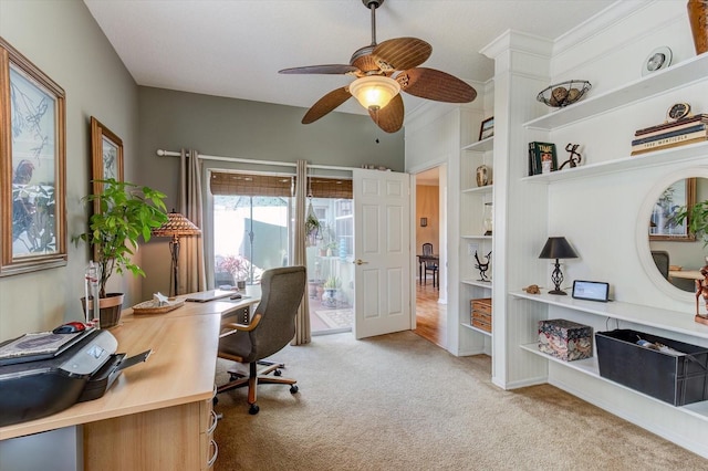 carpeted home office with ceiling fan and built in shelves