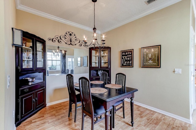 dining space featuring crown molding, a chandelier, and light hardwood / wood-style floors