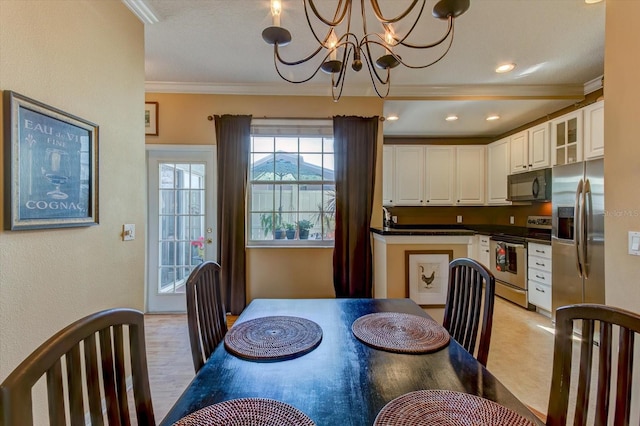 dining room featuring an inviting chandelier, ornamental molding, and light hardwood / wood-style floors