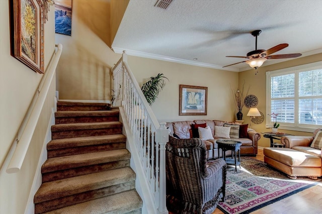 living room with hardwood / wood-style flooring, ceiling fan, ornamental molding, and a textured ceiling