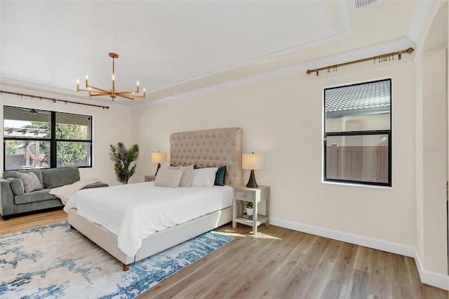 bedroom featuring ornamental molding, a tray ceiling, a chandelier, and wood-type flooring