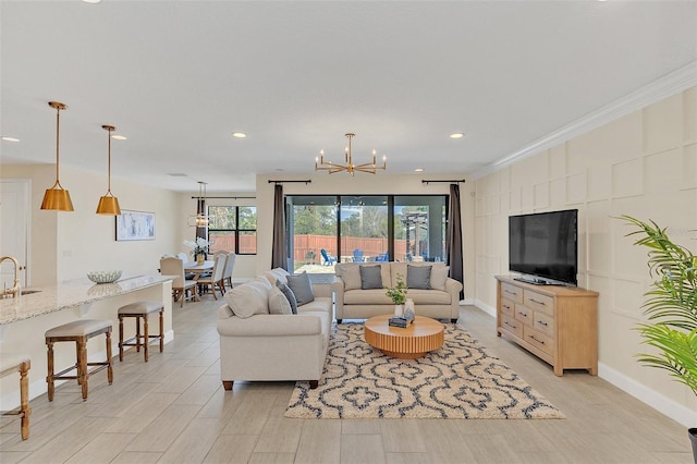 living room with ornamental molding, a chandelier, and light hardwood / wood-style flooring