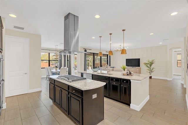 kitchen featuring pendant lighting, sink, light stone counters, and a center island