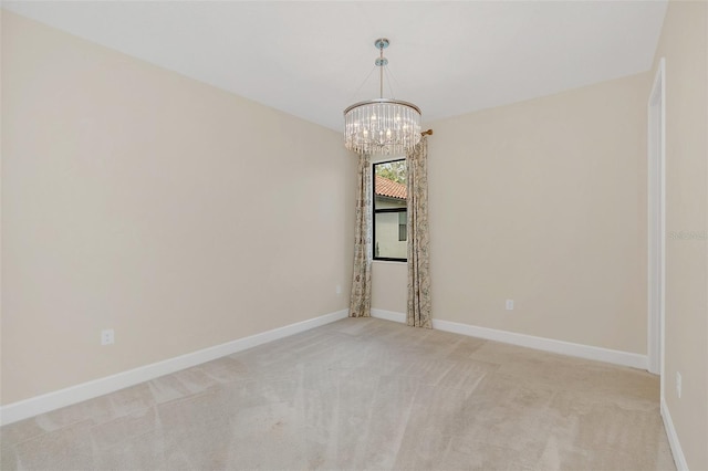 carpeted spare room with an inviting chandelier