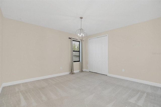 carpeted empty room featuring an inviting chandelier