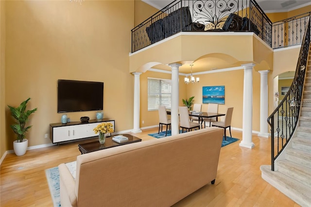 living room featuring decorative columns, wood-type flooring, ornamental molding, and a towering ceiling