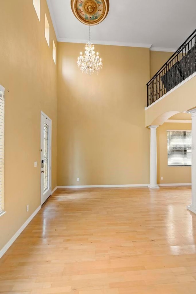 entryway featuring crown molding, decorative columns, and light wood-type flooring