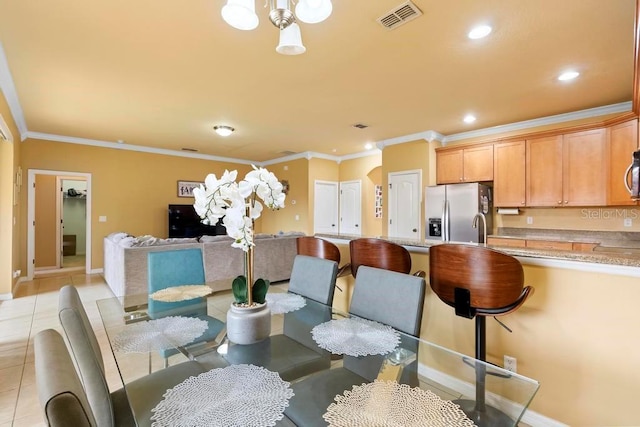 tiled dining space with an inviting chandelier, ornamental molding, and sink