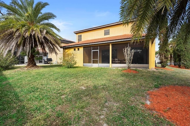 rear view of property featuring a sunroom and a lawn