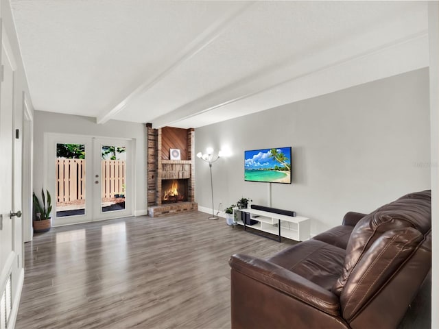 living room with a brick fireplace, beam ceiling, wood-type flooring, and french doors