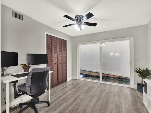 home office with light hardwood / wood-style floors and ceiling fan