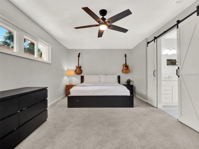 carpeted bedroom featuring sink, ensuite bath, a barn door, and ceiling fan