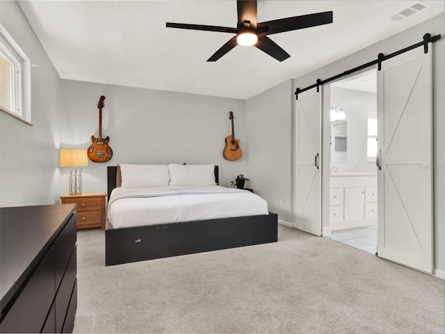 carpeted bedroom featuring ensuite bathroom, a barn door, and ceiling fan