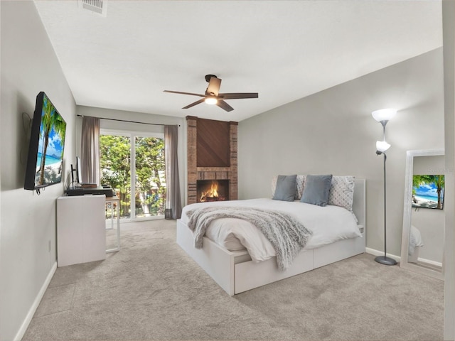 bedroom featuring a fireplace, light colored carpet, and ceiling fan