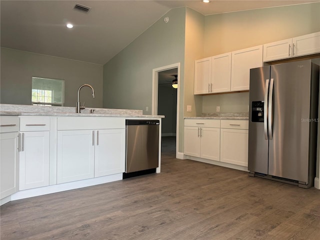 kitchen with hardwood / wood-style flooring, stainless steel appliances, white cabinetry, and lofted ceiling