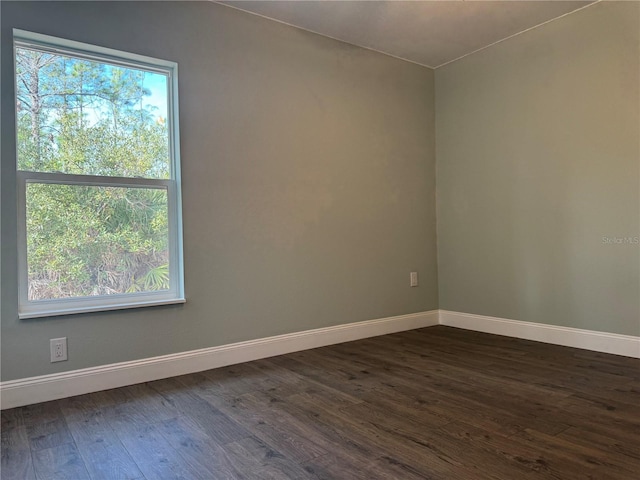 spare room featuring dark hardwood / wood-style flooring and a healthy amount of sunlight