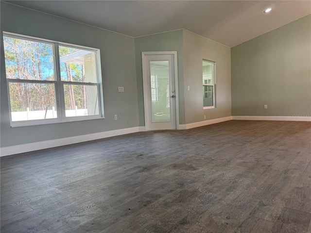 empty room with dark wood-type flooring and vaulted ceiling