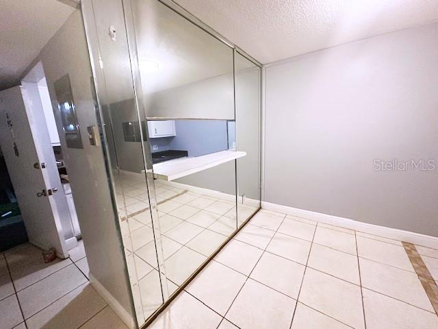 interior space with baseboards, a textured ceiling, and tile patterned floors