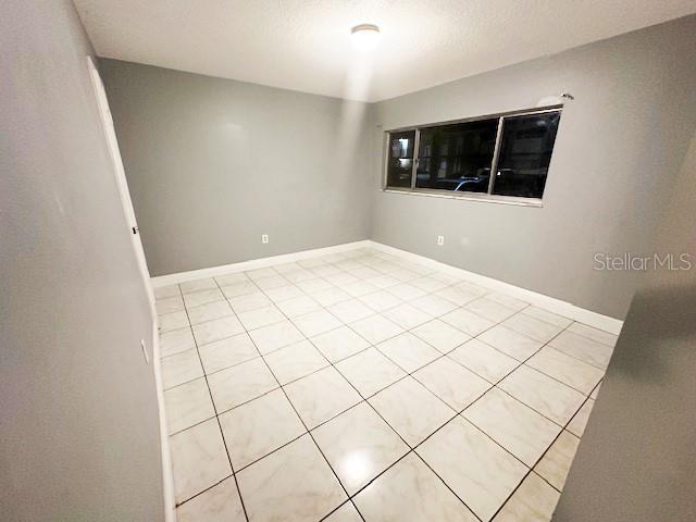 unfurnished room with light tile patterned floors and baseboards