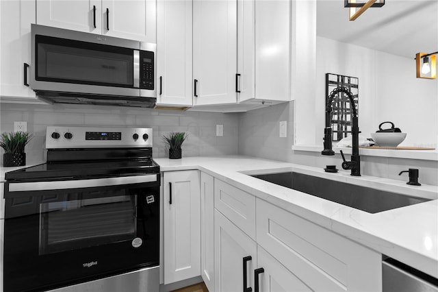 kitchen with white cabinetry, sink, light stone counters, and stainless steel appliances