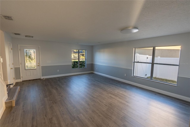 empty room with dark wood-type flooring and a textured ceiling