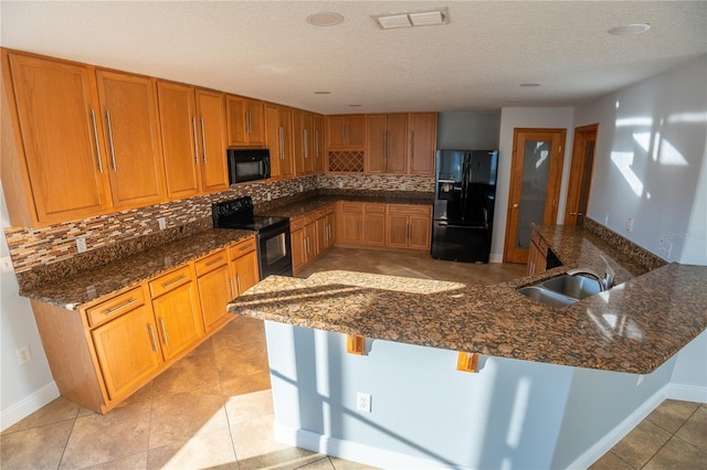 kitchen with sink, a breakfast bar area, tasteful backsplash, kitchen peninsula, and black appliances