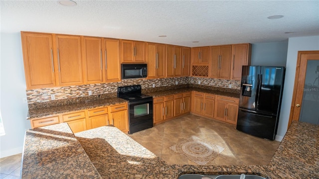 kitchen with a textured ceiling, decorative backsplash, dark stone counters, and black appliances