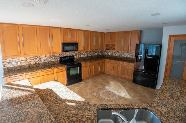 kitchen featuring dark stone countertops, backsplash, a textured ceiling, and black appliances