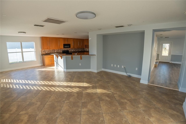 kitchen with a wealth of natural light, a breakfast bar area, tile patterned floors, and decorative backsplash