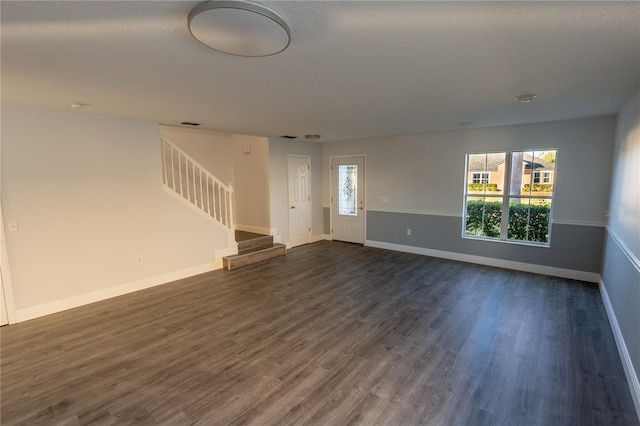 unfurnished living room featuring plenty of natural light and dark wood-type flooring