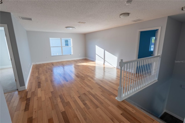 spare room with a wealth of natural light, light hardwood / wood-style flooring, and a textured ceiling