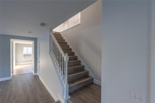 stairs featuring wood-type flooring and a textured ceiling