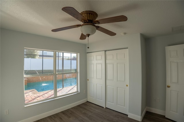 unfurnished bedroom with a closet, dark hardwood / wood-style floors, a textured ceiling, and a water view