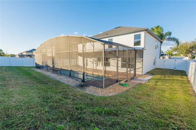 back of property featuring glass enclosure and a lawn