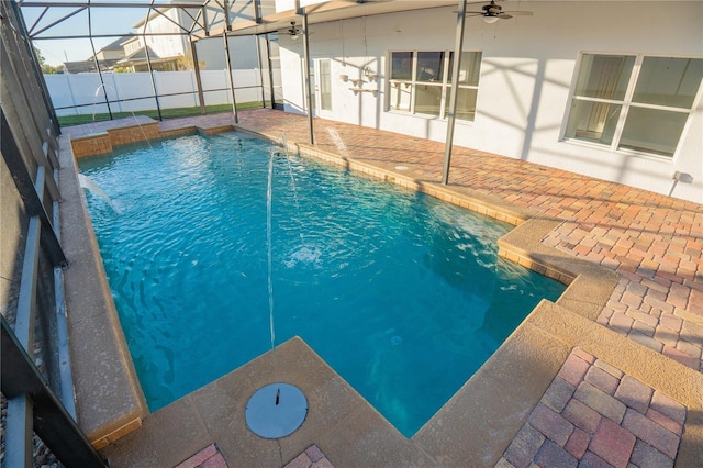 view of swimming pool with ceiling fan, pool water feature, glass enclosure, and a patio area