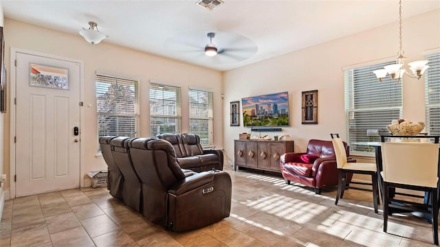 tiled living room with ceiling fan with notable chandelier