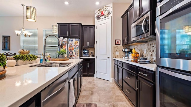 kitchen with appliances with stainless steel finishes, decorative light fixtures, sink, a chandelier, and decorative backsplash